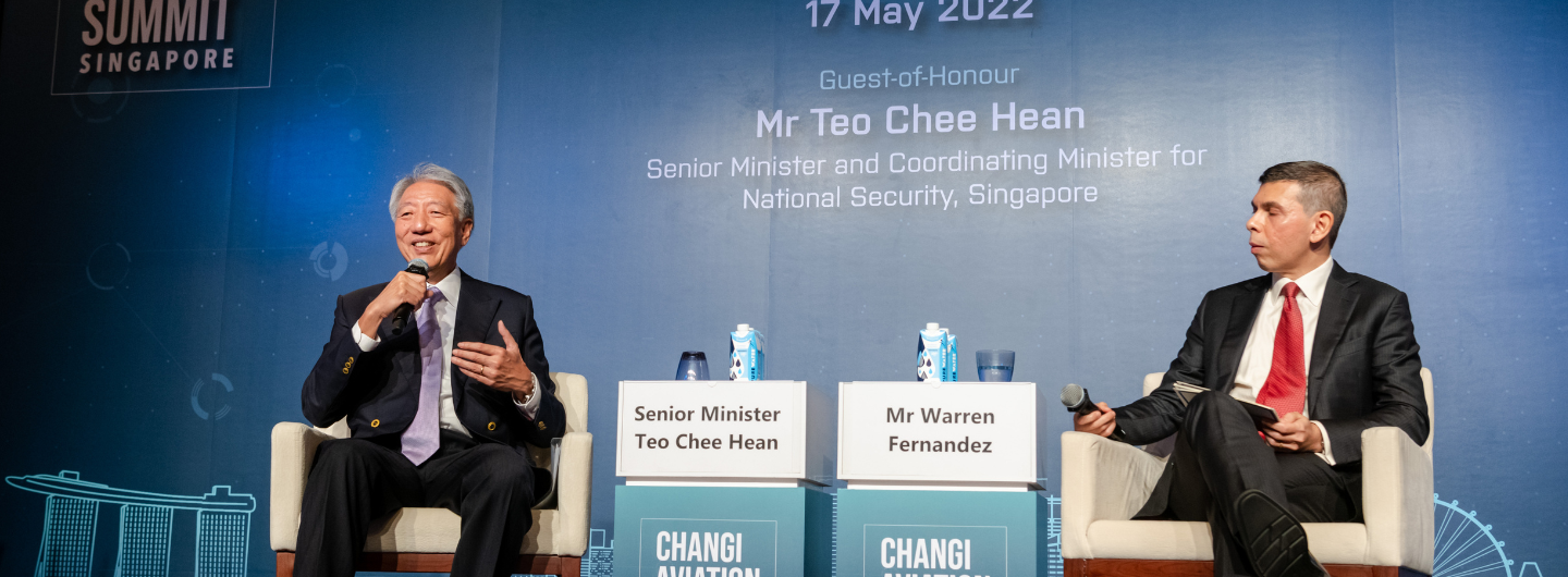 Two men in suits at Changi Aviation Summit, speaking at microphones on stage.